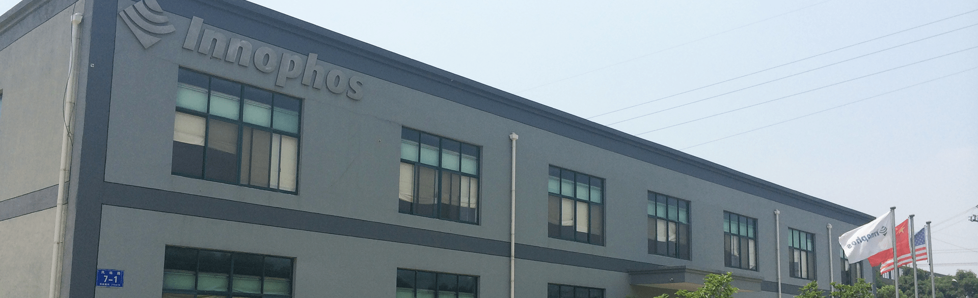 Two-story industrial building with Innophos branding, flags, and a street sign marked 358.