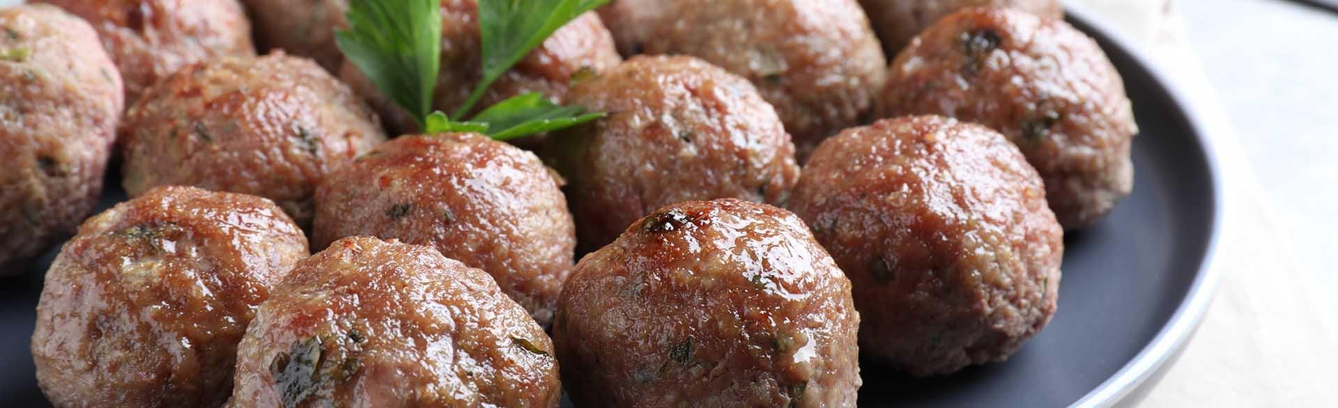 Plate of cooked meatballs garnished with parsley.