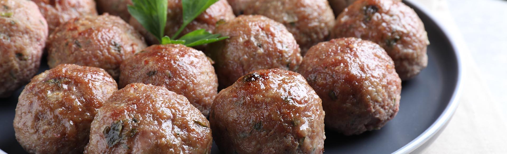 Plate of browned meatballs garnished with a sprig of parsley.
